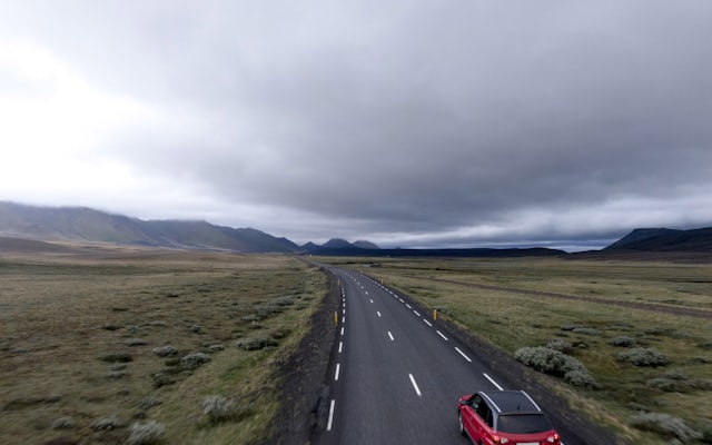 A red hatchback parked on an asphalt road