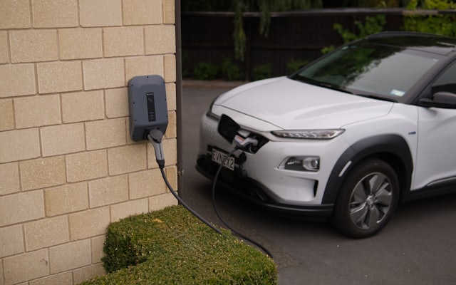 An electric car parked beside a brick wall