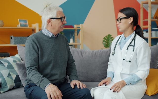 A doctor talking with an older patient at home