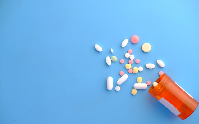 Prescription pills spilling from an orange bottle