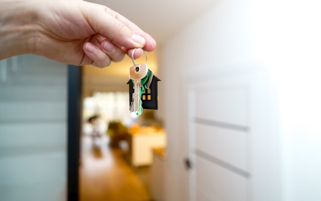 A hand holding house keys in a doorway